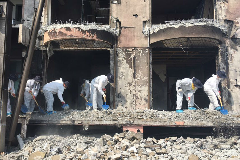 산불 피해를 입은 건물의 잔해물을 삽으로 치우는 공무원 봉사자들