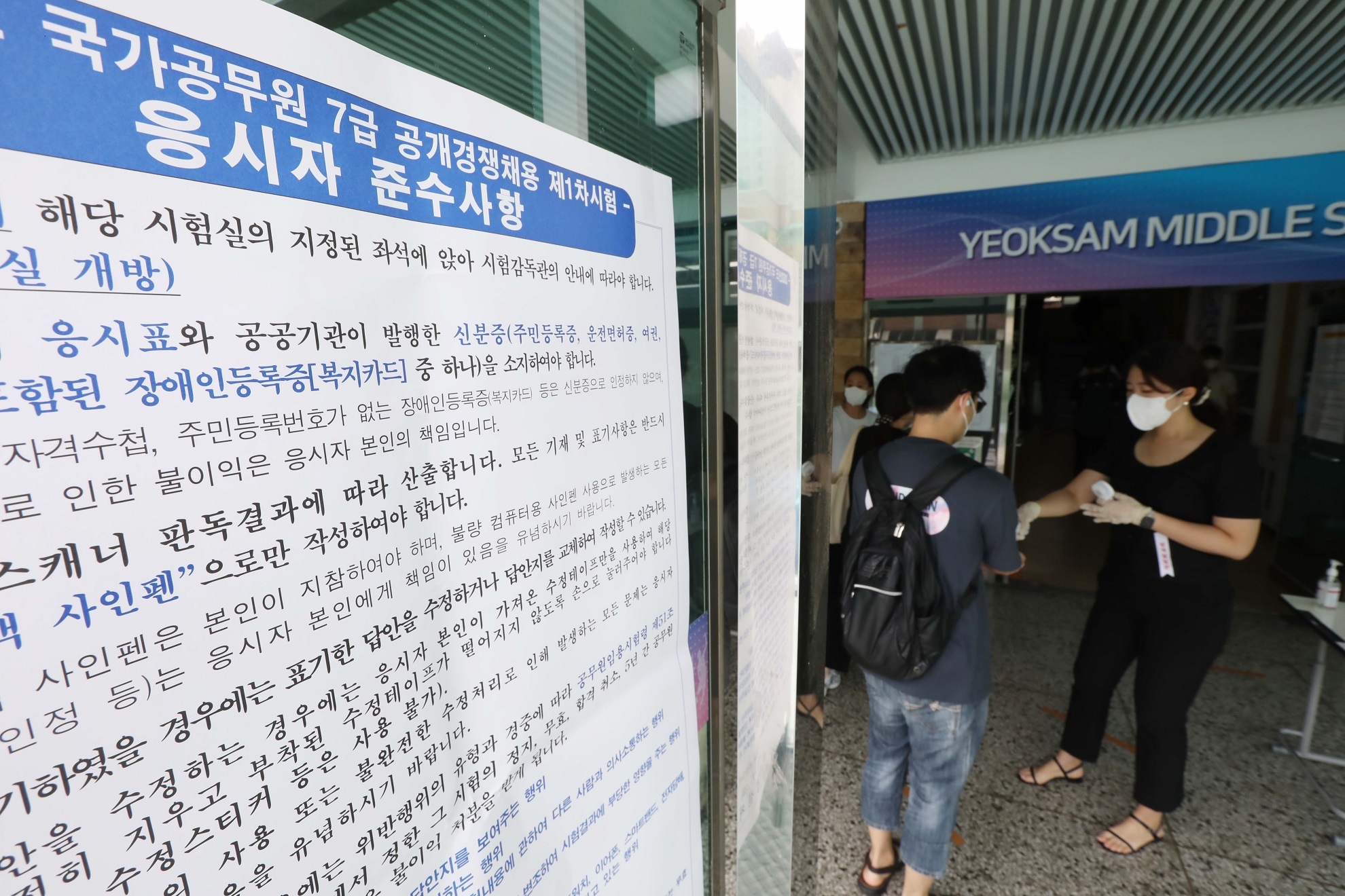 23일 국가공무원 7급 공개경쟁채용 제1차 시험장인 서울 강남구 소재 한 학교에 응시생이 입구에서 방역절차를 안내 받고 있는 모습
