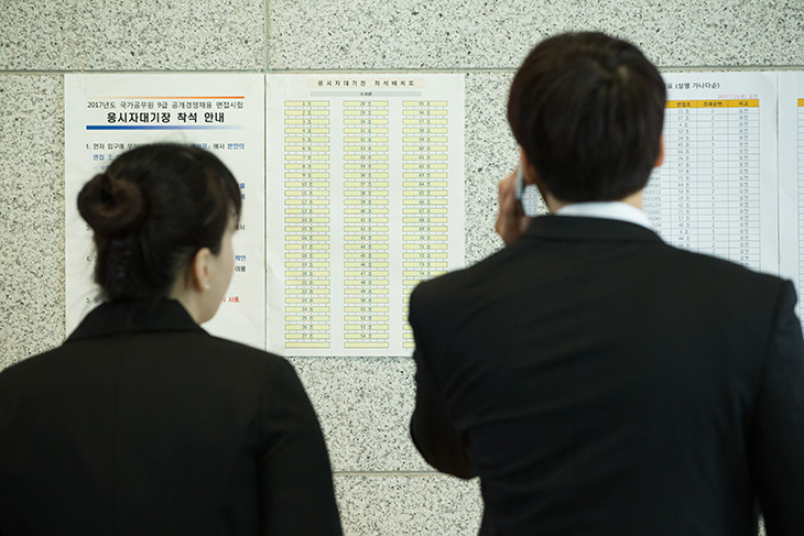 9급시험 배치도 및 안내문을 보고 있는 두 남녀의 뒷모습