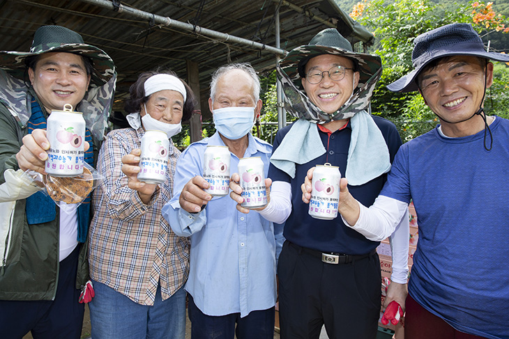 응원메시지가 담긴 음료수를 마시며 미소 짓는 봉사자들과 농민들