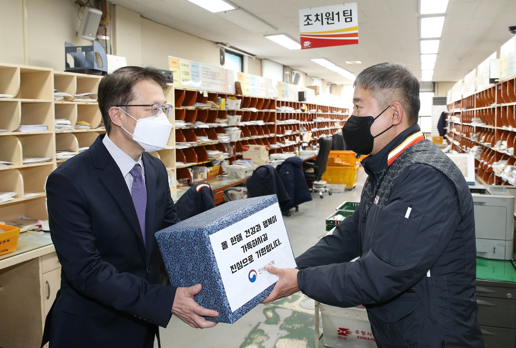 조성주 인사혁신처 차장(왼쪽)이 26일 세종시 조치원우체국을 방문해 설 명절을 앞두고 택배물량 증가 등으로 비상근무중인 우체국 직원 대표에게 전통시장에서 구매한 물품을 전달하는 모습