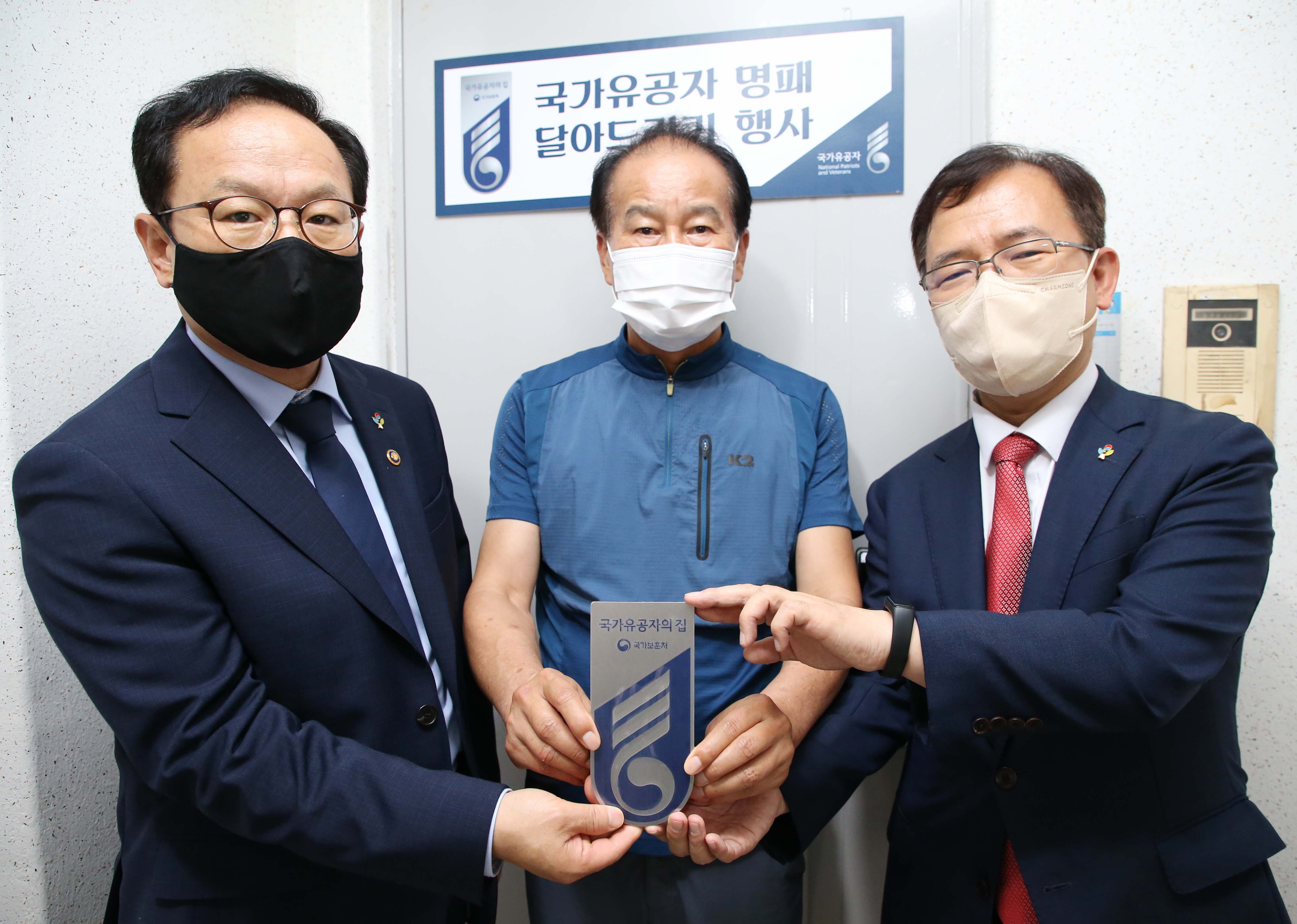 김승호 인사혁신처장(왼쪽)이 23일 호국보훈의 달을 맞아 황원채 대전지방보훈청장(오른쪽)과 대전시 대덕구에 거주중인 국가유공자 유족의 자택을 방문, '국가유공자의 집' 명패를 전달한 뒤 기념 촬영을 하는 모습